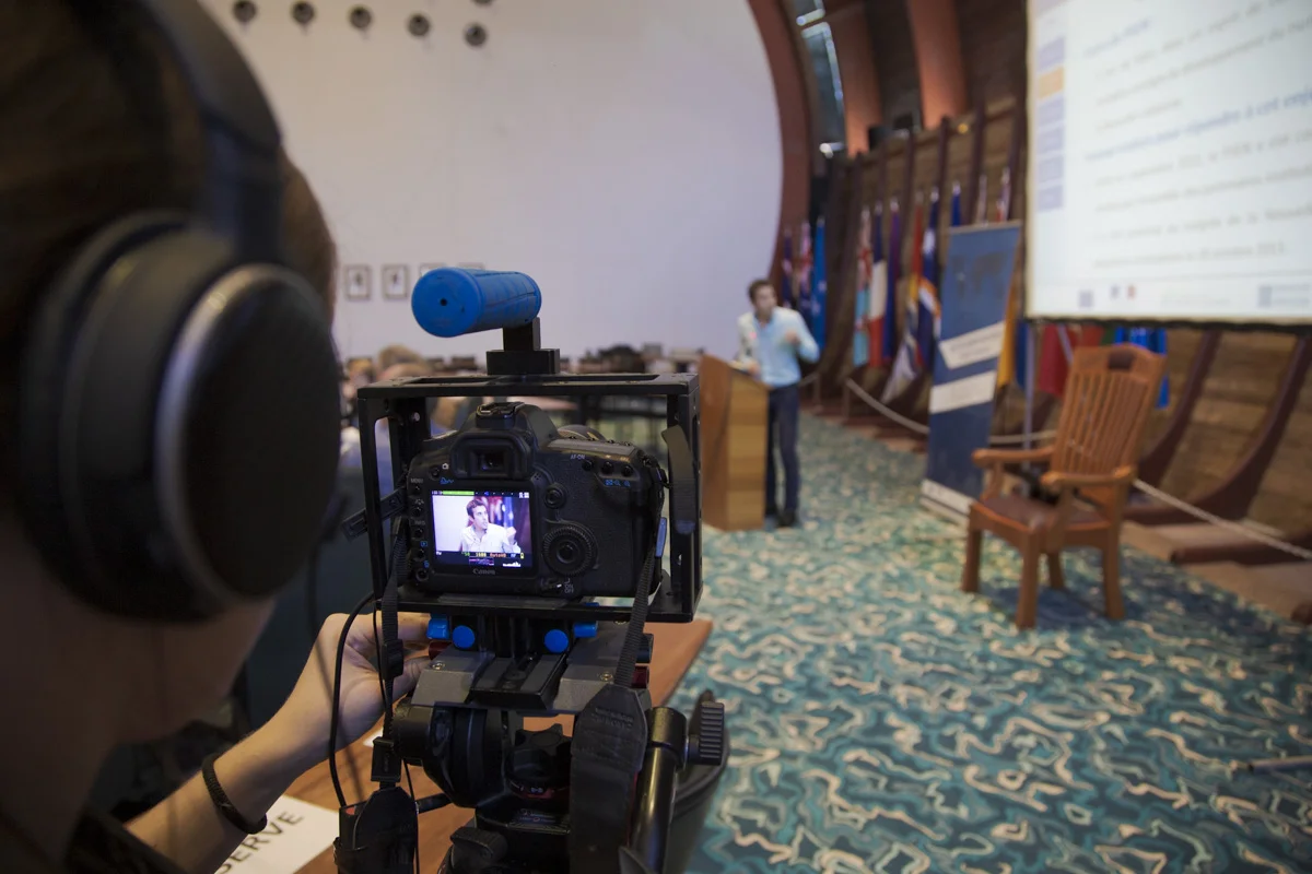 Gros plan sur le boiter d'un cameraman qui film un intervenant lors d'une conférence