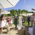 Photo des mariés avançant sous une pluie de pétales lancée par les invités qui sont autour