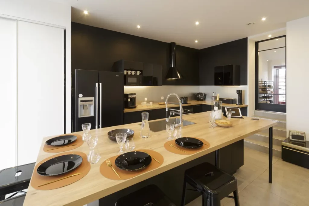 Photo d'une cuisine moderne noir, blanche et bois avec la table dressée sur l'îlot central