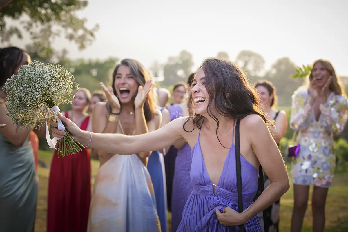 Photo d'un groupe de femmes dont l'un d'elle tend le bouquet de la mariée qu'elle vient probablement d'attraper au domaine de Lucain dans le Béarn