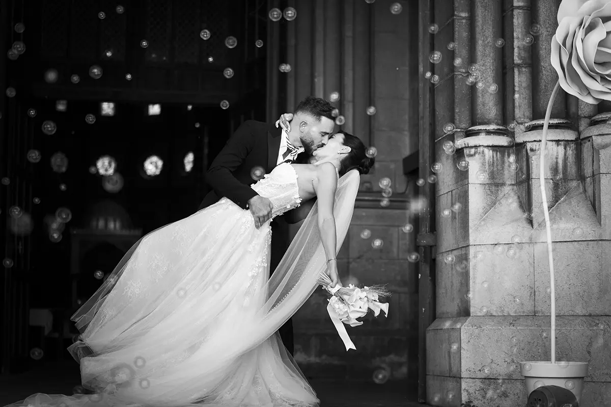 Photo en noir et blanc d'un couple s'embrassant amoureusement à la sortie de l'église de Pau avec des bulles qui volent autour