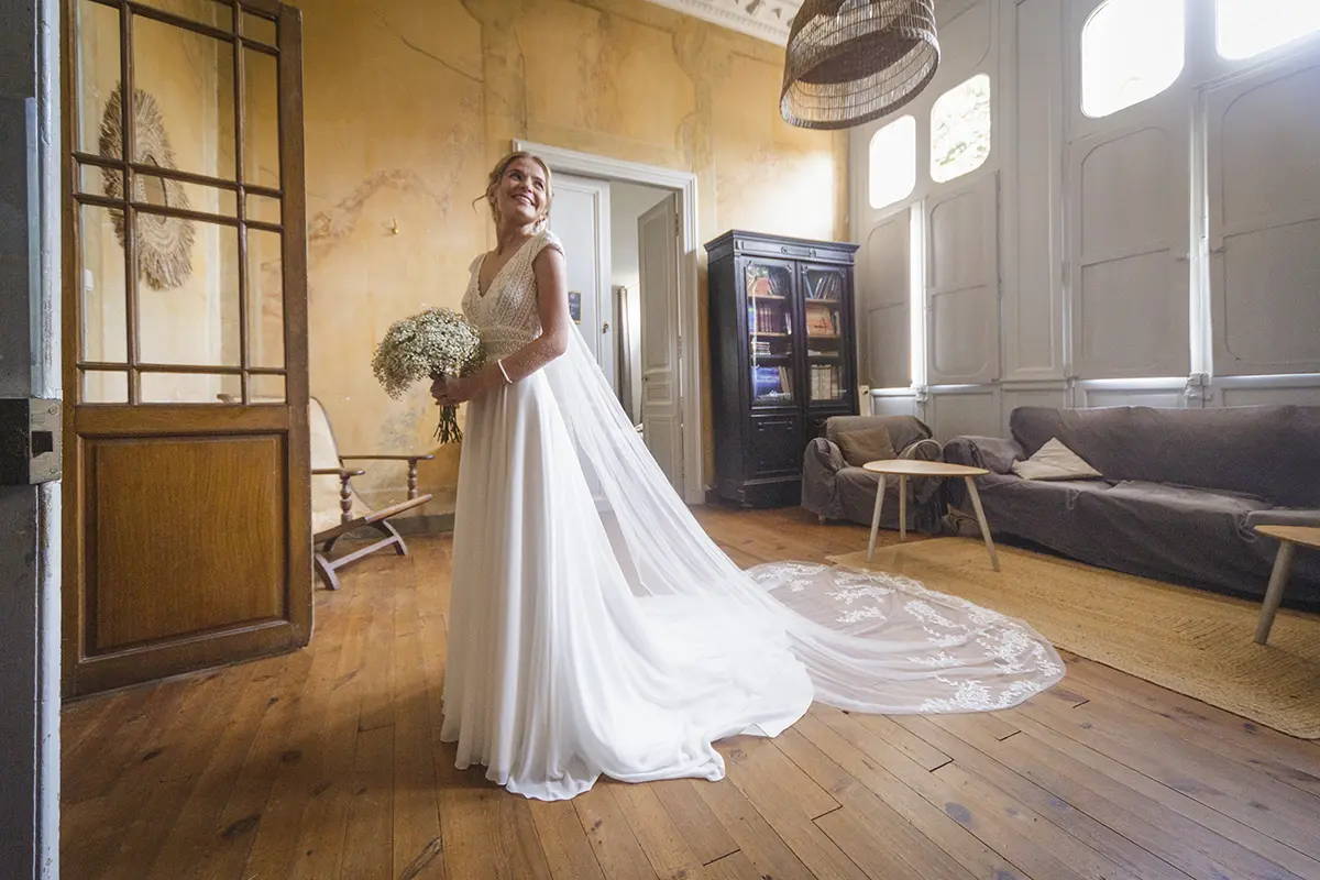 Photo de la mariée à la fin de ses préparatifs, elle sourie prête à sortir de la pièce