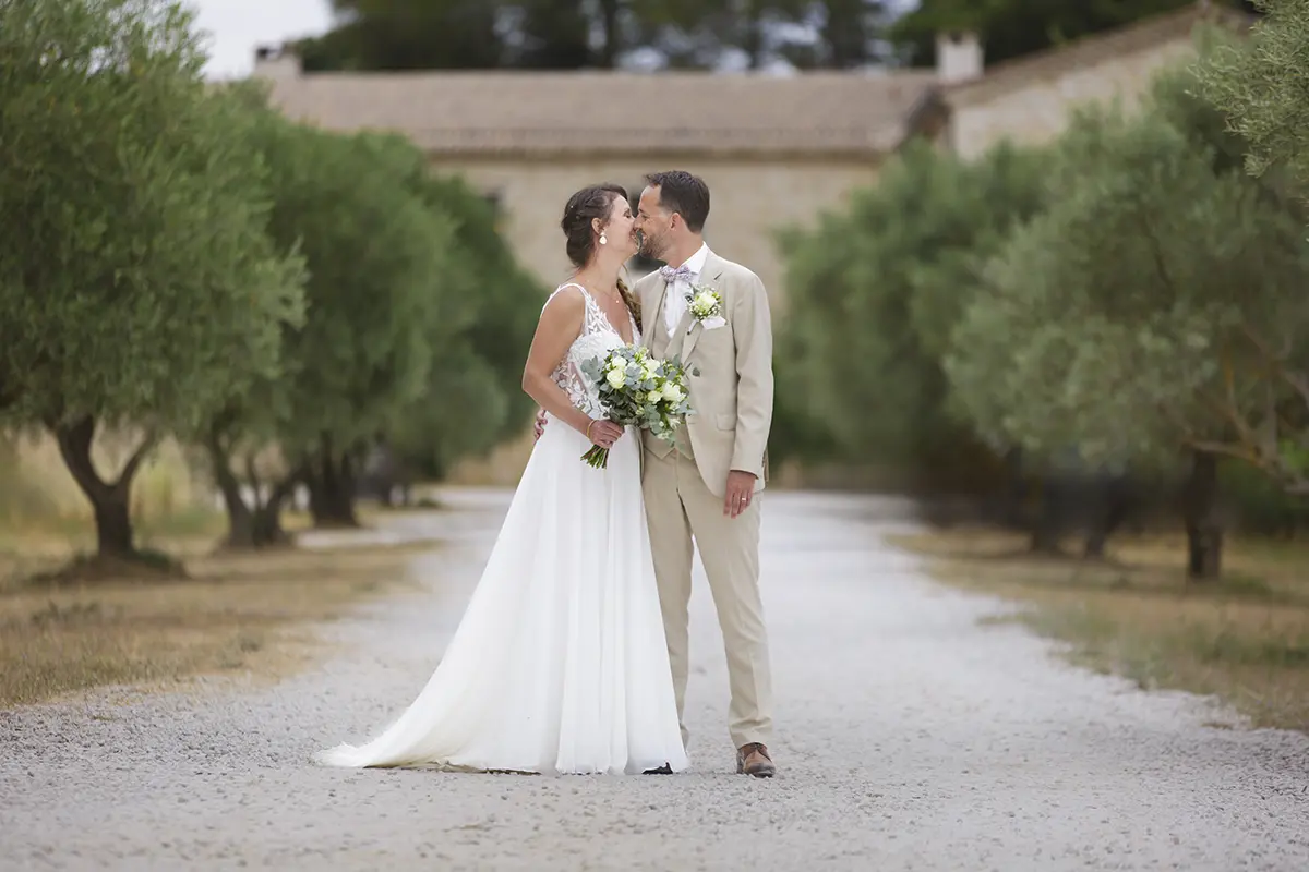 Photo d'un coupe de mariés s'embrassant dans une allée d'oliviers
